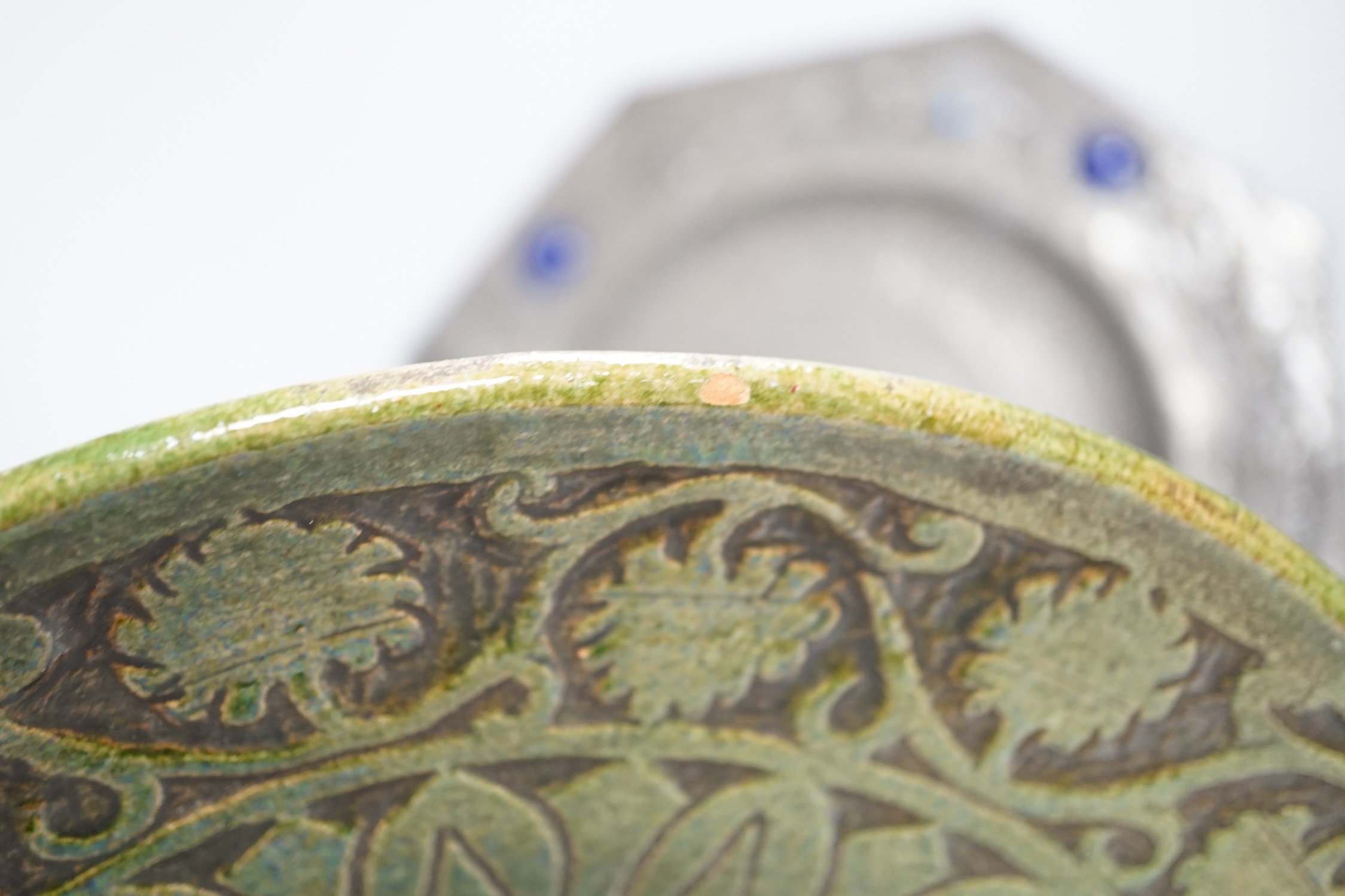 An Arts and Crafts style pewter fish plate with ceramic insets and glass eyes together with a pottery armorial charger, pewter charger 35cm wide